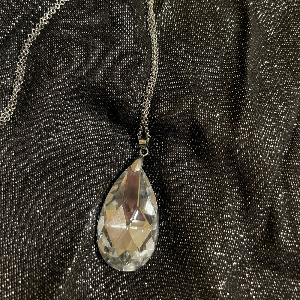Glamorous, long, silver-tone necklace with sparkling clear pendant.